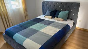 uma cama com um cobertor e almofadas azuis e brancas em Moradia Aroeira (Fonte da Telha Beach) em Aroeira