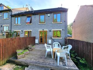a patio with chairs and a table in front of a house at 3 Bedroom Spacious Modern Comfortable Home in Rochdale, Work, Relax, Explore Manchester, Oldham, Bury in Rochdale