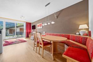 カプルーンにあるApartment Tauernblick Top3 by Four Seasons Apartmentsのダイニングルーム(テーブル、赤いソファ付)