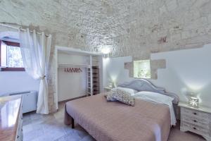 ein Schlafzimmer mit einem Bett und einer Steinmauer in der Unterkunft Trulli Elios in Cisternino