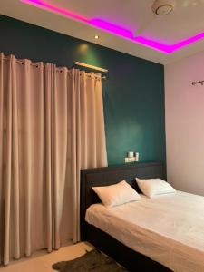 een slaapkamer met een bed met paarse verlichting bij Adole Guest House in Abomey-Calavi