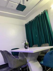 una mesa y sillas en una habitación con cortina verde en Adole Guest House en Abomey-Calavi
