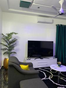 a living room with a couch and a large television at Adole Guest House in Abomey-Calavi