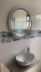 La salle de bains est pourvue d'un lavabo blanc et d'un miroir. dans l'établissement Adole Guest House, à Abomey-Calavi