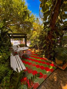 un jardín con un banco y una alfombra de flores rojas en Pousada Estalagem do Porto, en Arraial do Cabo