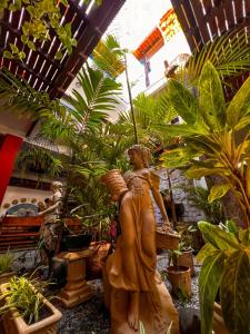 une statue d'une femme dans une pièce avec des plantes dans l'établissement Pousada Estalagem do Porto, à Arraial do Cabo