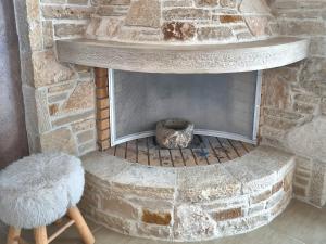 - une cheminée en pierre avec un tabouret devant dans l'établissement Haroupia The Residence, à Kalidhón