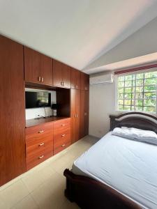 a bedroom with a bed and a tv and wooden cabinets at Habitación privada in Panama City