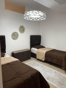 1 dormitorio con 2 camas y lámpara de araña en Romantic chalet between swimming pools and close to the seashore, en Áqaba