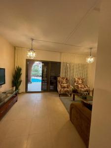 sala de estar con sofá, sillas y TV en Romantic chalet between swimming pools and close to the seashore, en Áqaba