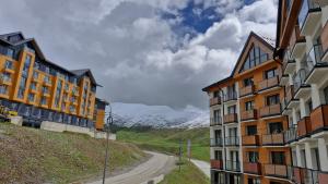 two buildings on a dirt road with mountains in the background at SkyWay Twins Studio Gudauri in Gudauri