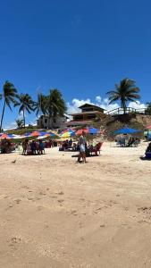 eine Gruppe von Menschen mit Sonnenschirmen an einem Strand in der Unterkunft Apartamento Praia do Francês in Marechal Deodoro