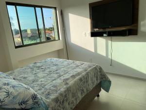 ein Schlafzimmer mit Bett und Flachbildfernseher in der Unterkunft Apartamento Praia do Francês in Marechal Deodoro