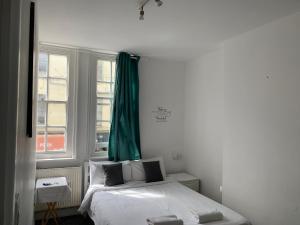 1 dormitorio con 1 cama con cortina verde en Brick lane stay, en Londres 27 fotos más