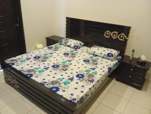 a bedroom with a bed with a floral comforter and pillows at Balqees Cottage in Lahore