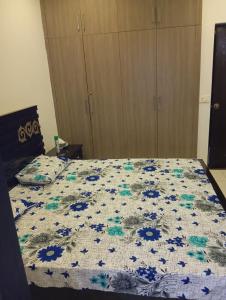 a bed with a blue and white quilt on it at Balqees Cottage in Lahore