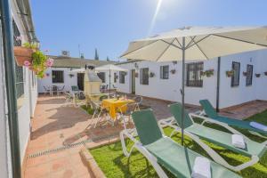 eine Terrasse mit einem Tisch, Stühlen und einem Sonnenschirm in der Unterkunft Casa Rural Rivero in Posadas