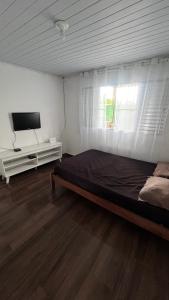 a bedroom with a bed and a flat screen tv at Iguape, Jureia, Barra do Ribeira - Frente ao mar in Iguape