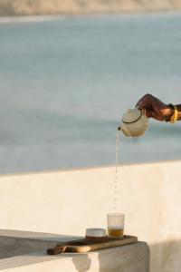 a person pouring tea from a teapot into a glass at The O Experience - Tayourt Lodge in Imsouane +15 photos