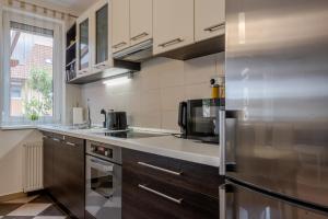 a kitchen with a stainless steel refrigerator and cabinets at Six Corners Sunny Corner Apartment with Terrace in Pécs