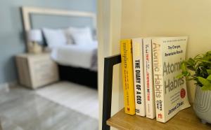 grupa książek siedzących na półce obok łóżka w obiekcie Evans Village - Stunning Apartments w mieście Johannesburg