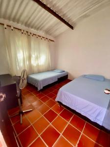 two beds in a room with a red tile floor at El Palmar in Guaduas
