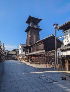 a large building with a tall tower on a street at R House 川越 in Kawagoe