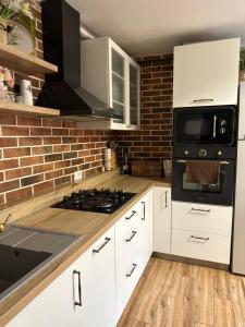 a kitchen with white cabinets and a brick wall at Hanul Anei - entire property in Braşov
