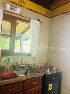 uma cozinha com um lavatório, um fogão e uma janela em Morada Crisálida em Praia do Rosa