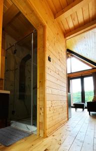 a glass shower in a room with a wooden wall at Woodland Noszvaj in Noszvaj