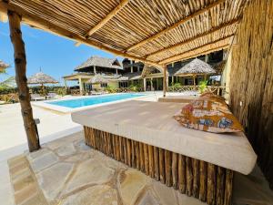 a bed under a pergola next to a pool at Ocean zuri villa in Watamu