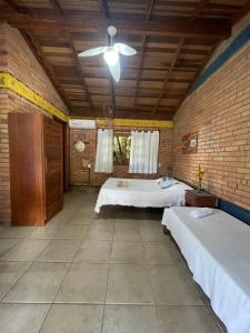 a room with two beds and a brick wall at Morada Crisálida in Praia do Rosa
