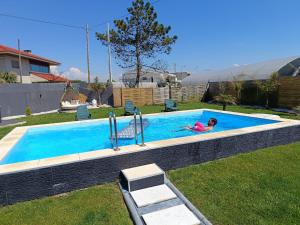 a woman laying in a swimming pool in a yard at sand and sea in Póvoa de Varzim