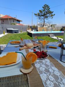 a table with plates of food and oranges on it at sand and sea in Póvoa de Varzim