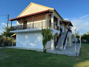 a white house with a porch and stairs on it at Gian Petro Apartments in Sidari