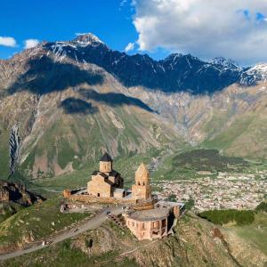 an old building on a hill with mountains in the background at Crystal Kazbegi in Kazbegi