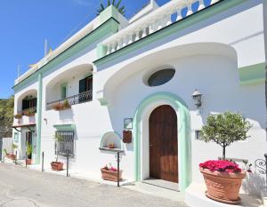 un edificio blanco con puerta de madera y macetas de flores en Villa Eleonora, un angolo di Paradiso ad Ischia en Isquia