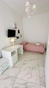 een witte kamer met een bed en een bureau bij Casa Vacanze De Gasperi 210 in Castellammare di Stabia
