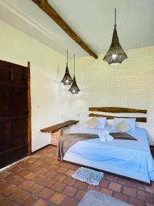 a bedroom with a bed with blue sheets and pendant lights at Rancho do Buna in Atins