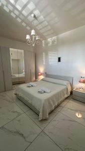 een witte slaapkamer met een groot bed en een kroonluchter bij Casa Vacanze De Gasperi 210 in Castellammare di Stabia