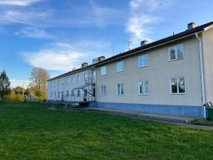 a large white building with a grass field next to it at Davids Hotell in Alvesta