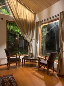 ein Wohnzimmer mit 2 Stühlen und einem großen Fenster in der Unterkunft Nigeen Vista Lakeside Chalet in Srinagar