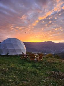 a tent and two chairs on a field with a sunset at Yenokavan Glamping in Ijevan