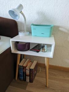 a white table with a lamp and books on it at Vintage-Zimmer mit Balkon in Felsberg