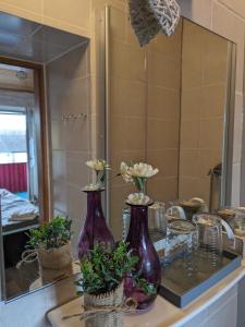 two purple vases sitting on a counter in front of a mirror at Vintage-Zimmer mit Balkon in Felsberg
