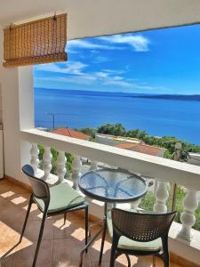 balcón con mesa, sillas y vistas al océano en Villa Stipuka en Brela