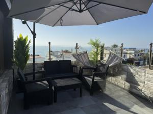 eine Terrasse mit einem Sonnenschirm, 2 Stühlen und einem Tisch in der Unterkunft Villa Serenade 3 etage in Moulay Bousselham