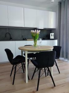 a dining room table with chairs and a vase of flowers at Apartament u Moniki in Międzywodzie