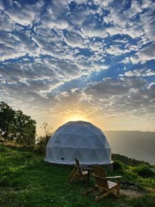 Yenokavan Glamping في إيجيفان: خيمة و كرسيين على تلة مع غروب الشمس