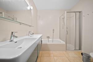 ein weißes Bad mit einem Waschbecken und einer Dusche in der Unterkunft Apartment SKI & GOLF Kaprun by Four Seasons Apartments in Kaprun